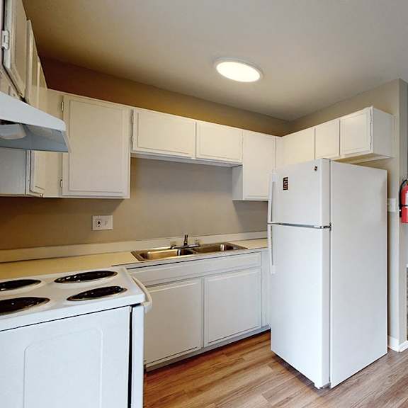 a kitchen with white appliances and wooden floors.