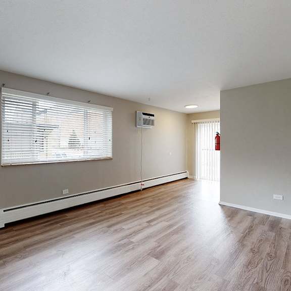 a room with wooden flooring and a window with blinds.