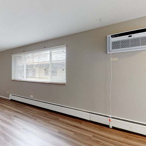 a room with a wooden floor and a window with blinds.