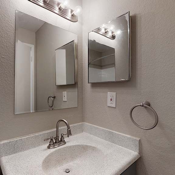 a bathroom with a sink, mirror, and light fixture.