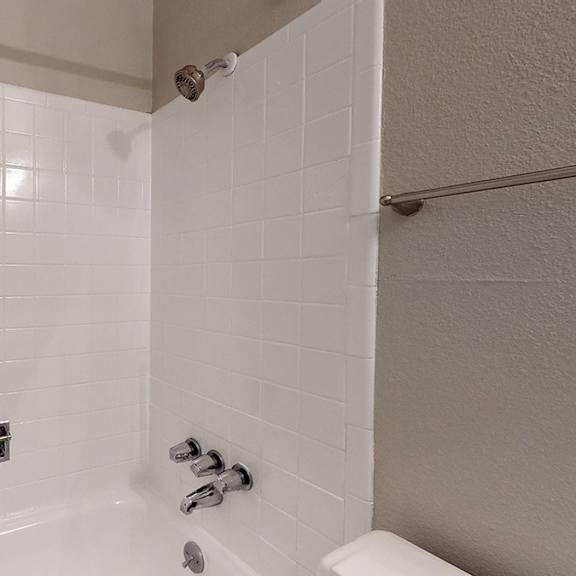 a white tiled shower with a shower head and faucet.