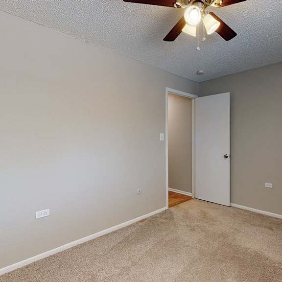 a room with a ceiling fan and carpeted floor.