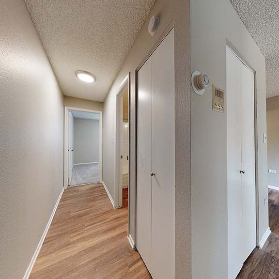 a hallway with white walls and wood flooring.