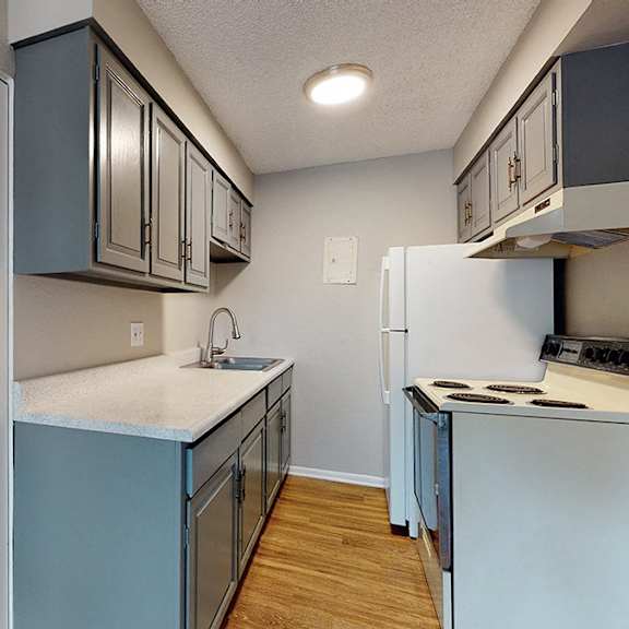 a kitchen with a refrigerator, sink, and cabinets.