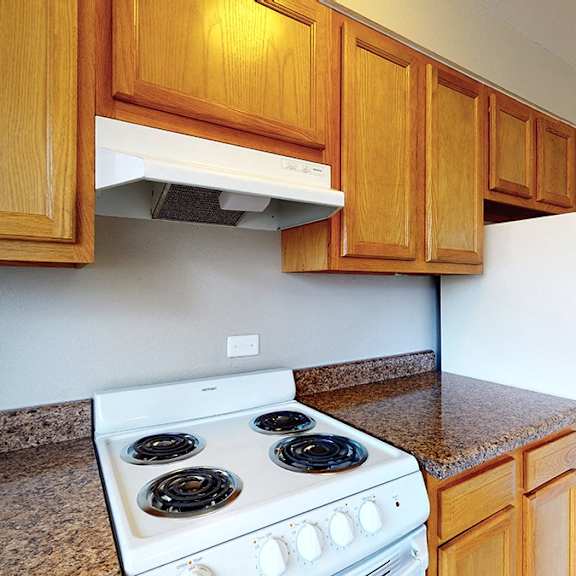 a kitchen with a white stove and wooden cabinets.