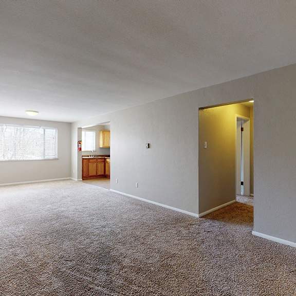 a large, empty room with carpeted flooring and a door on the right.