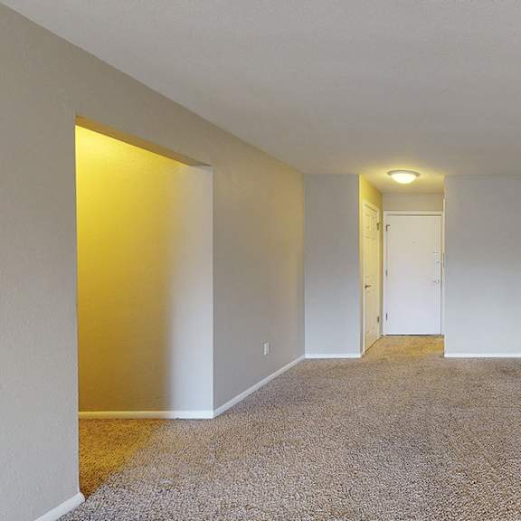 a carpeted room with a doorway leading to another room.