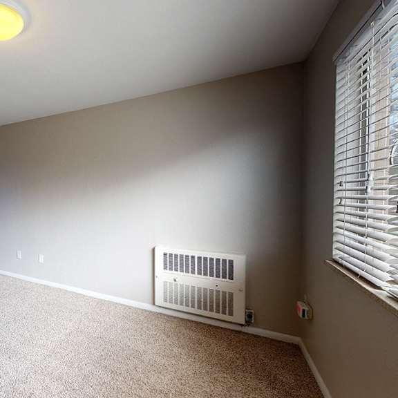 a room with a carpet floor and a window with blinds.