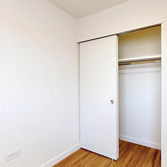 a white door is open to a small room with a wooden floor.
