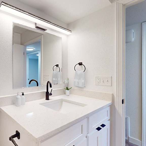 a bathroom with a white sink and a framed picture on the wall.