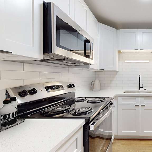 a modern kitchen with white cabinets and stainless steel appliances.
