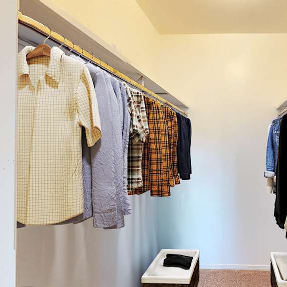 a row of clothes hanging on a rail in a room.