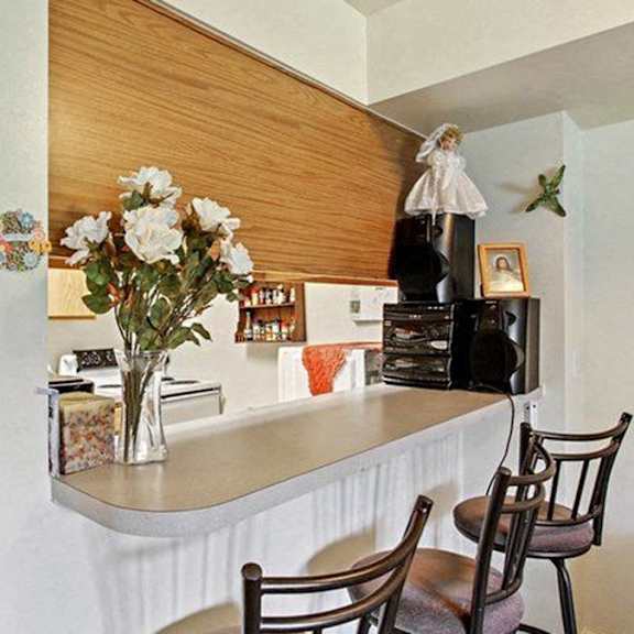 a kitchen with a white counter and a vase of white flowers.