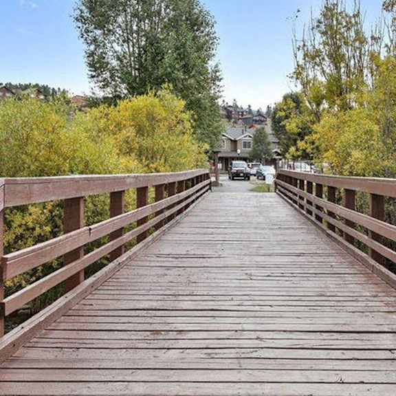 a wooden bridge over a river with trees on both sides.