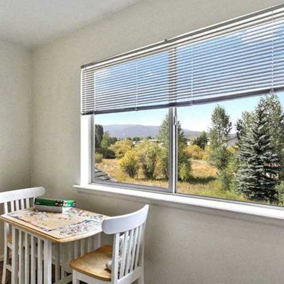 a room with a table and chairs by a window with a view of trees outside.