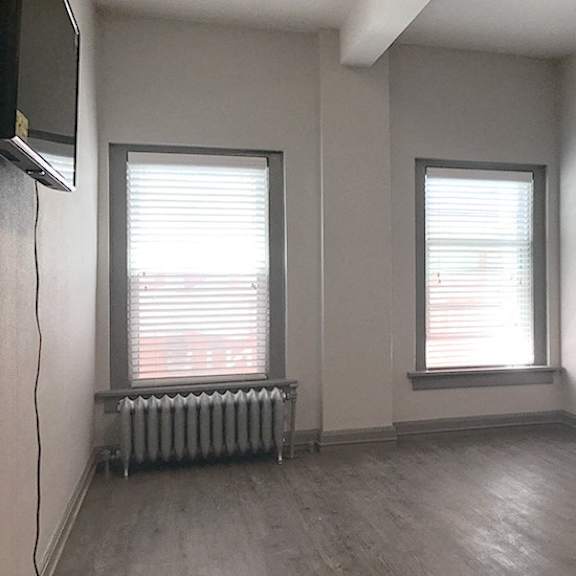 a room with two windows and a radiator.