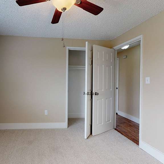 a room with a ceiling fan and a window with blinds.