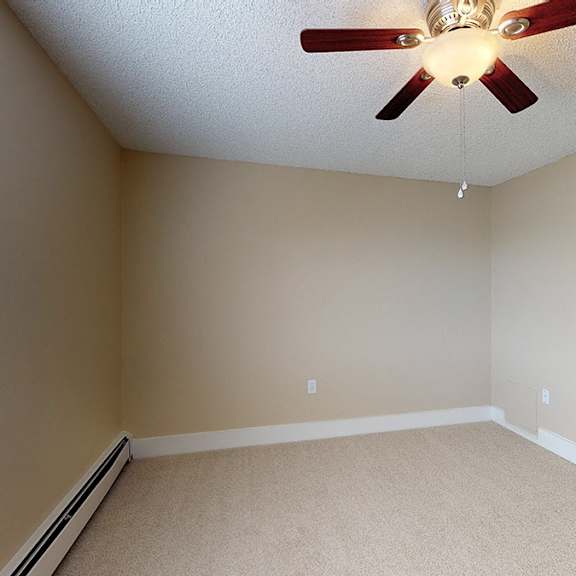 a room with a ceiling fan and carpeted floor.
