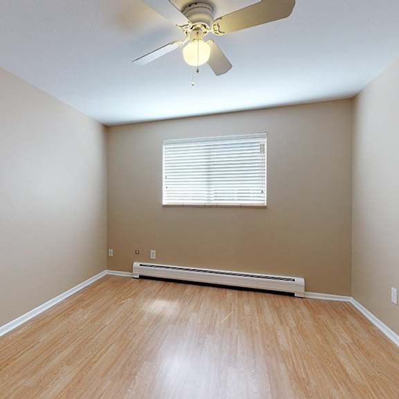 a room with a ceiling fan and a window with blinds.