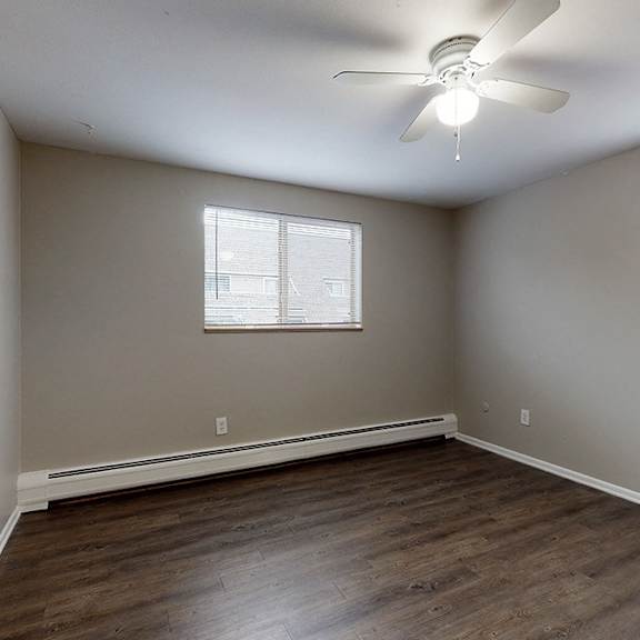 a room with a ceiling fan and two windows.