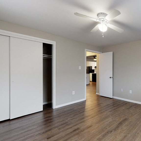 a room with a ceiling fan and wooden floors.