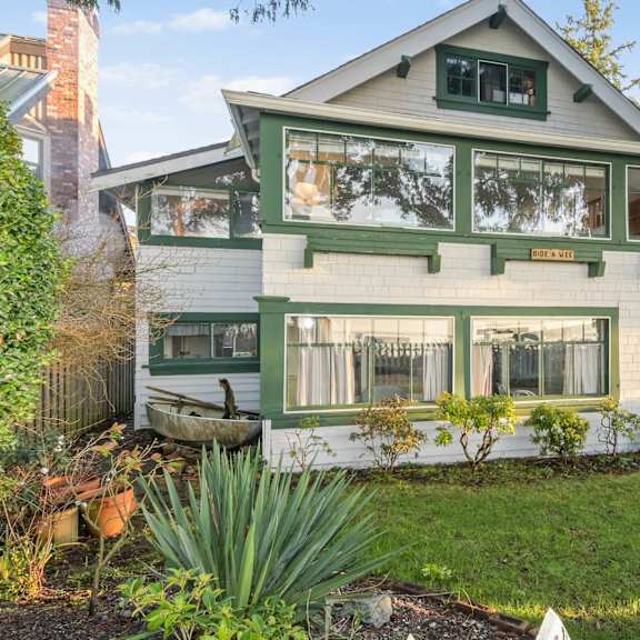 a green and white house with a white picket fence in front.
