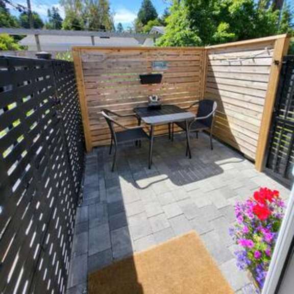 a patio with a bench and a table surrounded by a wooden fence.