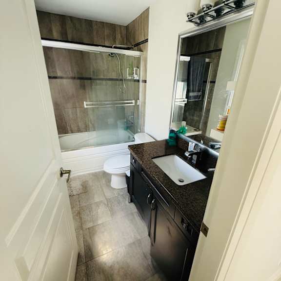 a bathroom with a toilet, sink, and shower.