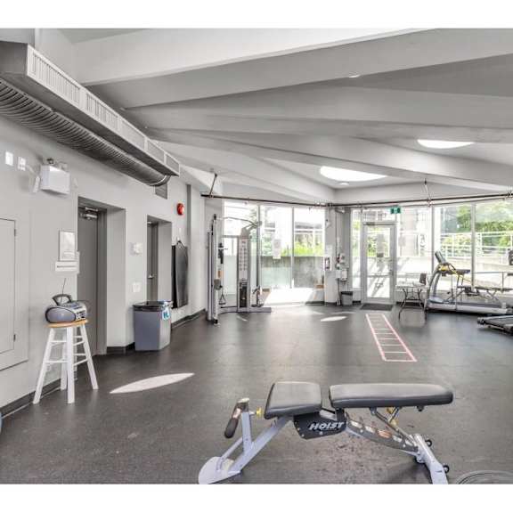 a gym with a variety of equipment including a treadmill, weights, and a bench.