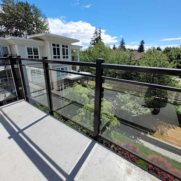 a modern building with a glass balcony overlooking a sidewalk.