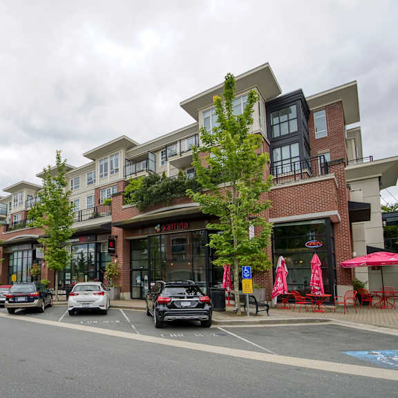 a street view of a row of apartment buildings with cars parked in front.