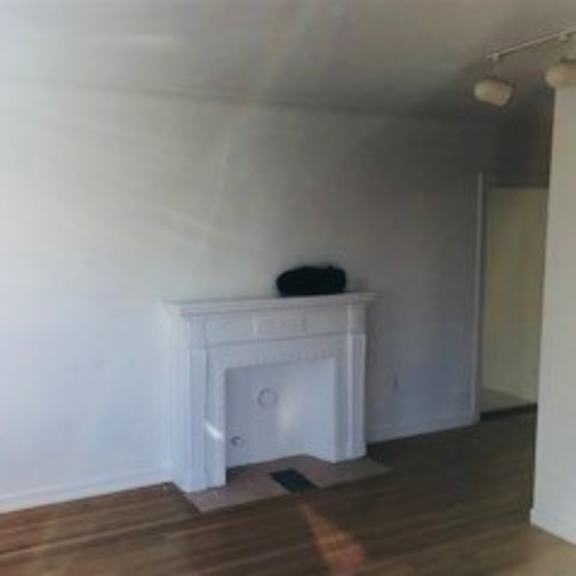 a white fireplace in a room with wooden floors and white walls.
