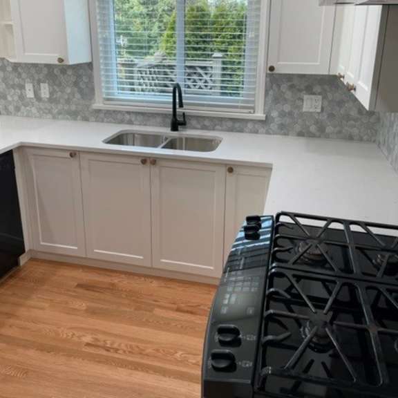 a kitchen with a black stove top oven and a window with blinds.