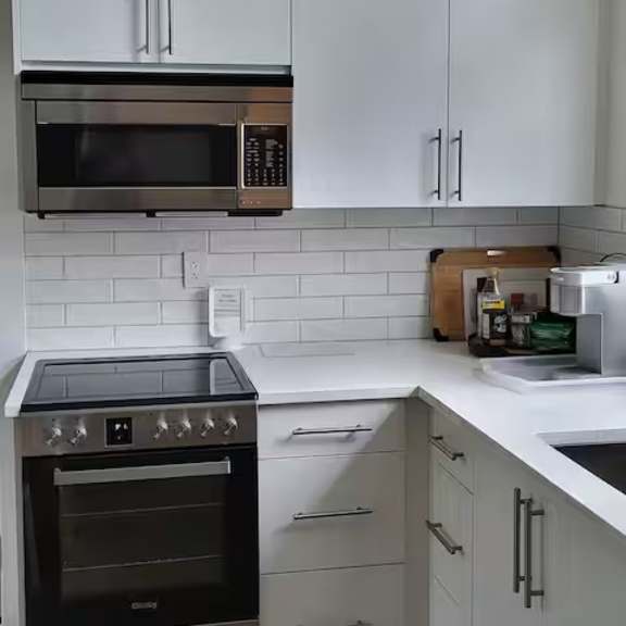 a kitchen with white cabinets and a black stove top oven.