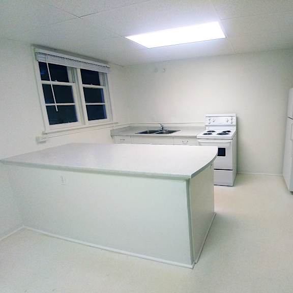 a white room with a window, a fridge, and a sink.