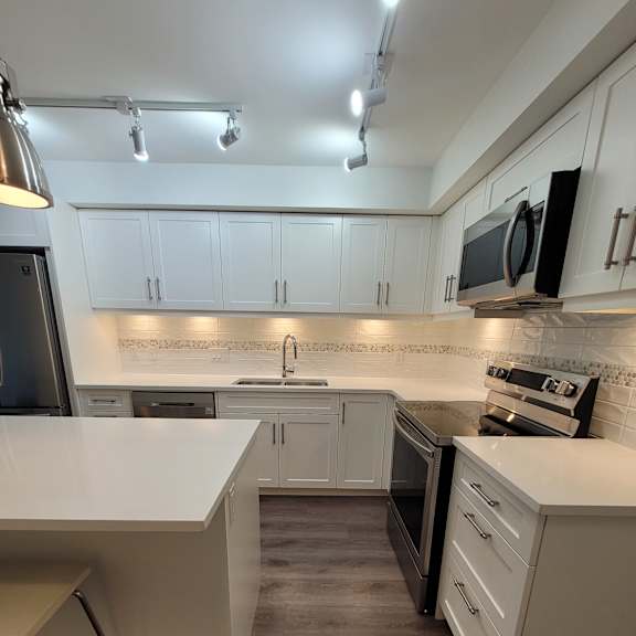 a modern kitchen with white cabinets and a wooden wall.