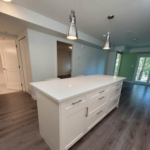 a white kitchen with wooden floors and a window.