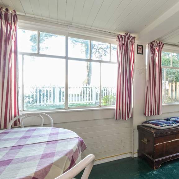 a room with a table and chairs and a bench with a window in the background.