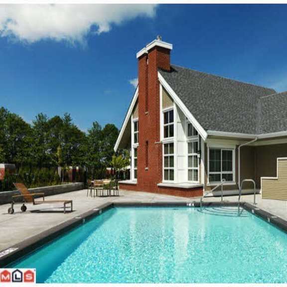 a pool in front of a house with a deck and a hot tub.