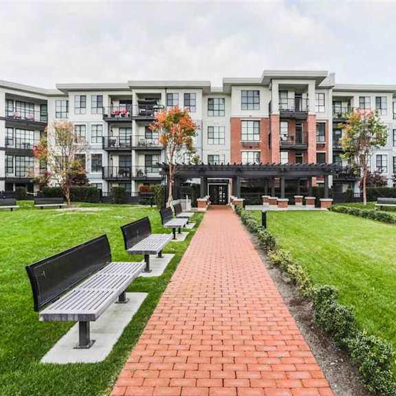 a brick walkway leads to a building with balconies.