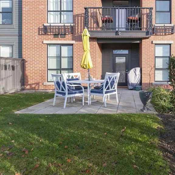 a patio with a table and chairs is in front of a brick building.
