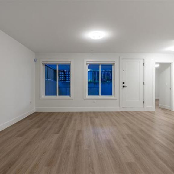 a room with wooden flooring and two windows with blue curtains.