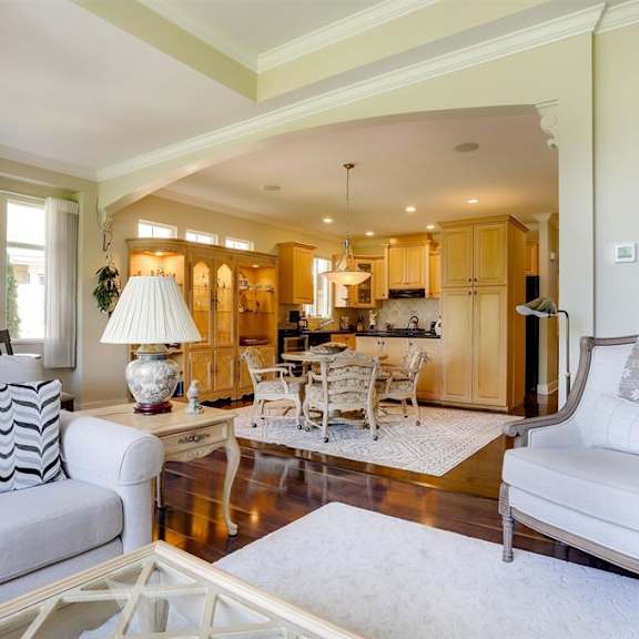 a living room with a white sofa, a glass coffee table, and a painting on the wall.