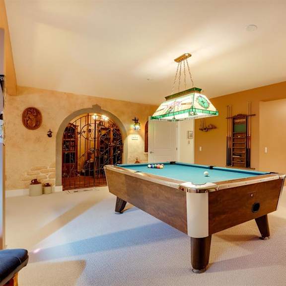 a pool table is in the middle of a room with a couch and a chair.