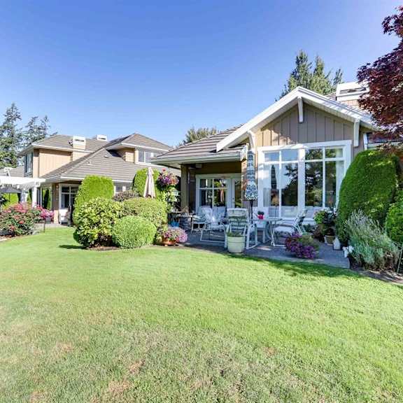 a house with a well-maintained lawn and a variety of plants.