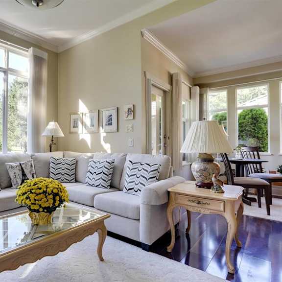 a living room with a white couch, a glass coffee table, and a ceiling fan.