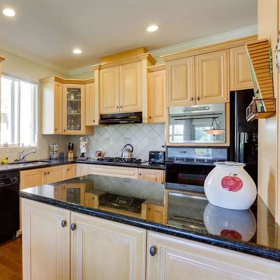 a kitchen with wooden cabinets and black countertops.