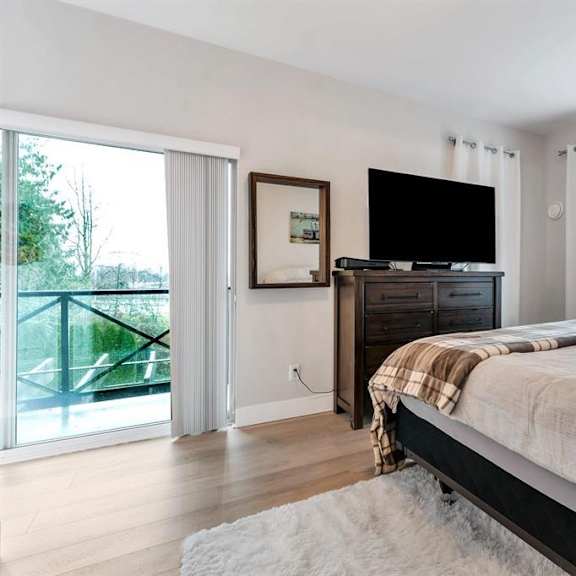 a bedroom with a large bed, a flat screen tv, and sliding glass doors.