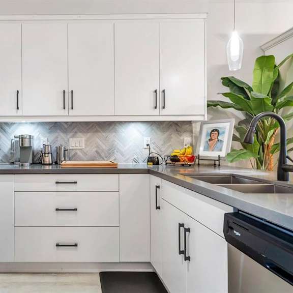 a modern kitchen with white cabinets and a black stove top.