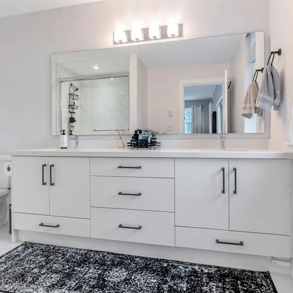 a bathroom with a white toilet, sink, and cabinets.